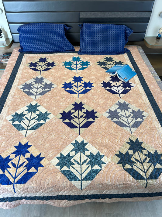 Handmade blue and cream patchwork quilt displayed on a queen-size bed.