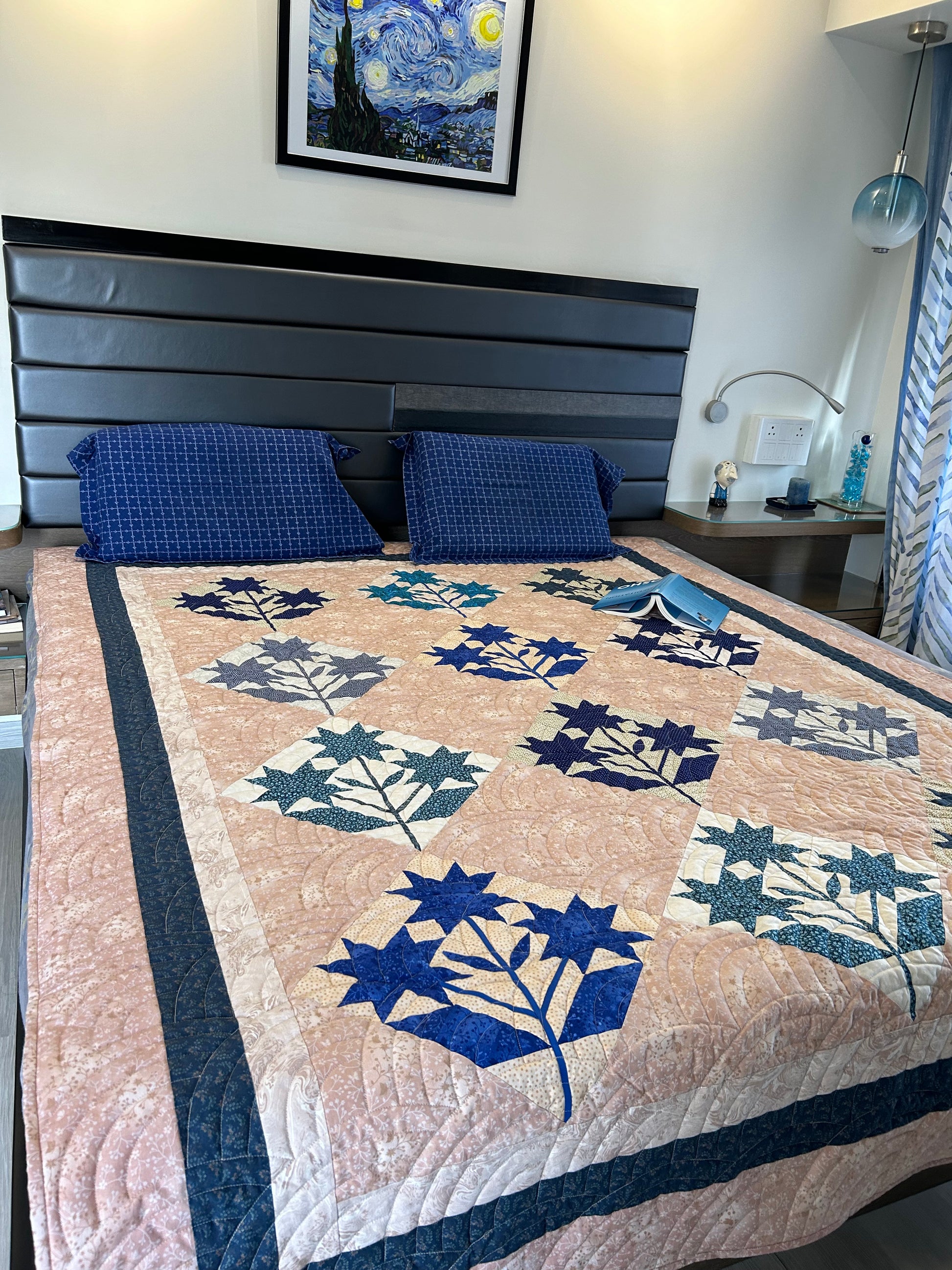 Handmade blue and cream patchwork quilt displayed on a queen-size bed.