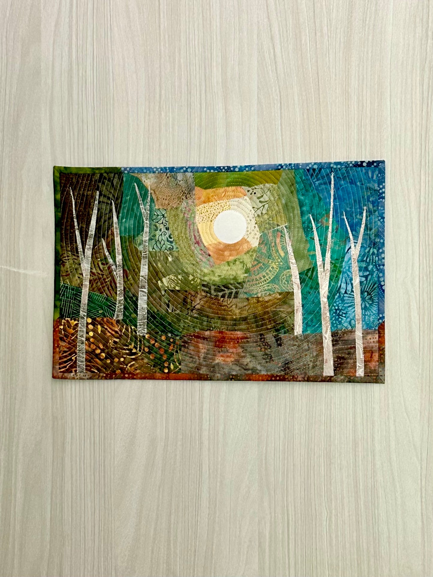 Jungle landscape quilt – front view of the tropical fiber art in blue and green.