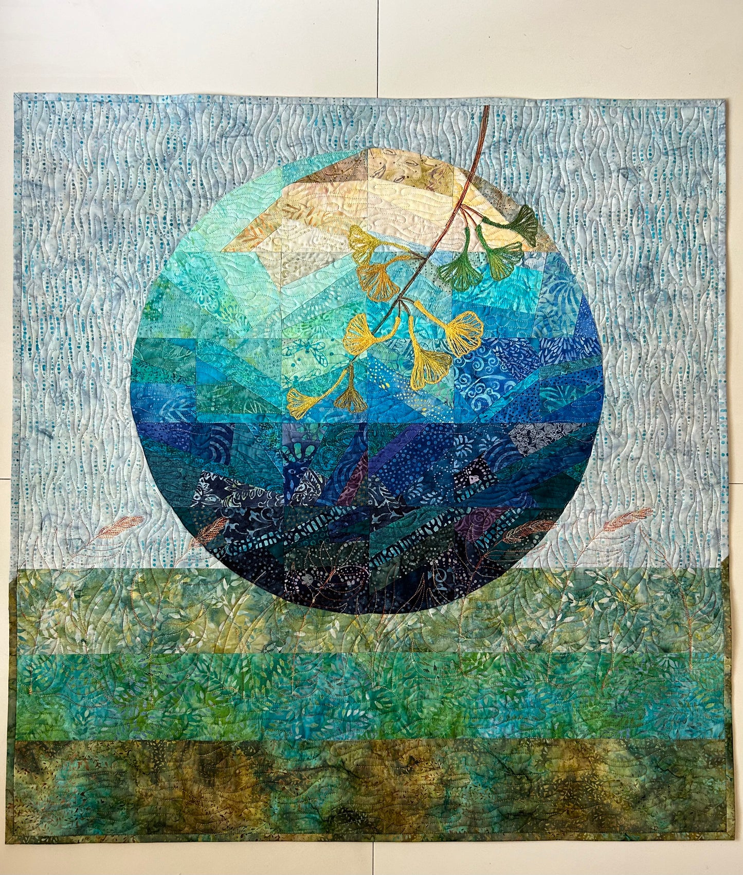 Abstract lunar art quilt – front view of moon-inspired blue and green fiber art.