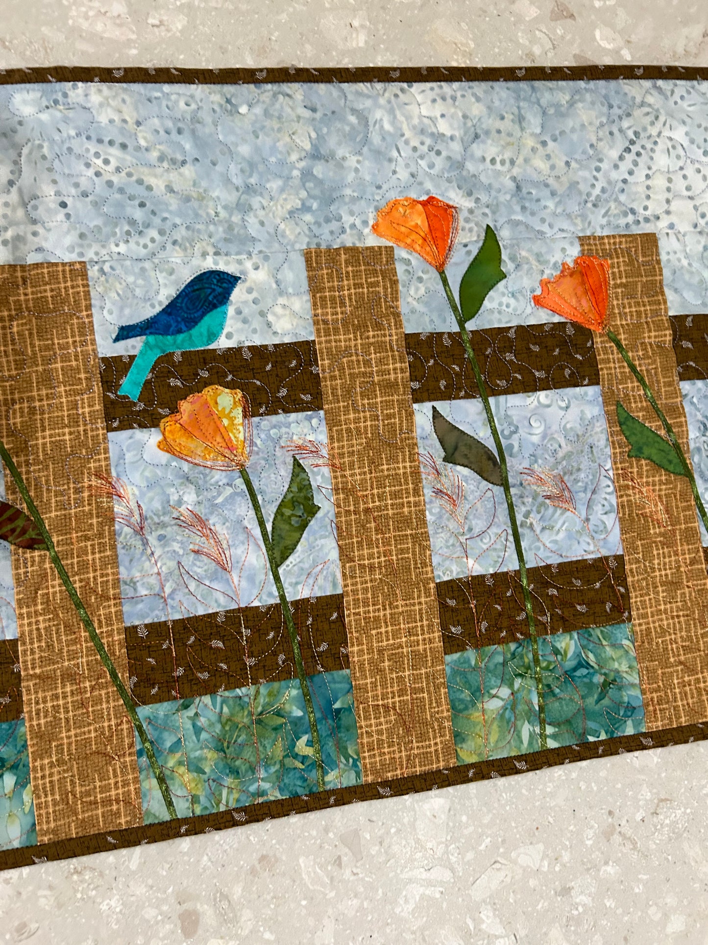 Close up of table runner showing bird appliqué and orange colour flowers