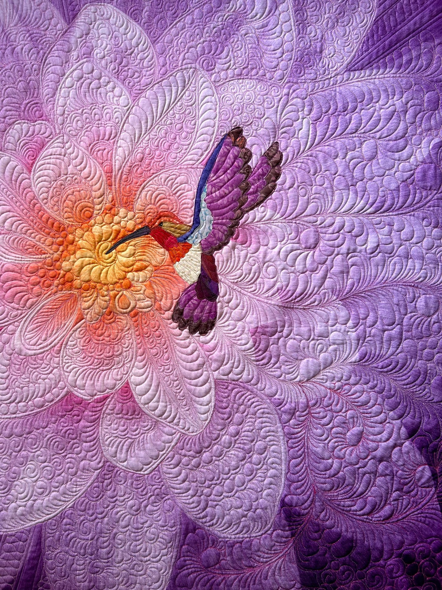 Handcrafted purple flower quilt with hummingbird appliqué.