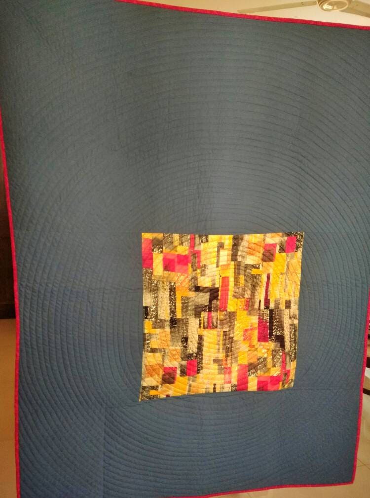 Handmade spiral patchwork quilt in gray and yellow gold.