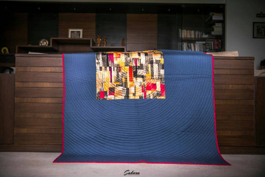 Modern throw quilt draped over couch with geometric layout.