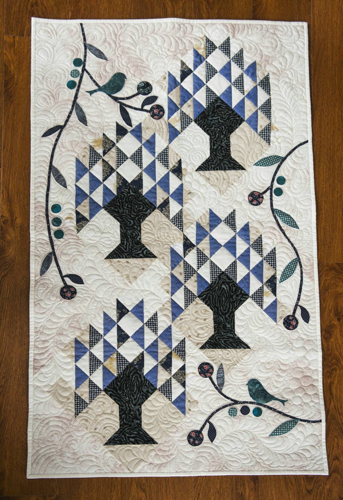 Blue and cream tree of life quilt laid down on the wooden floor
