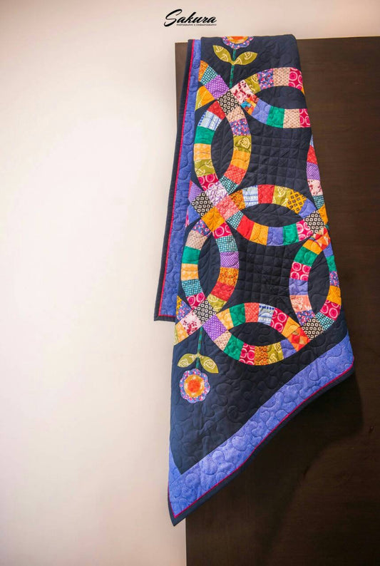 Handmade blue double wedding ring throw quilt displayed on a door