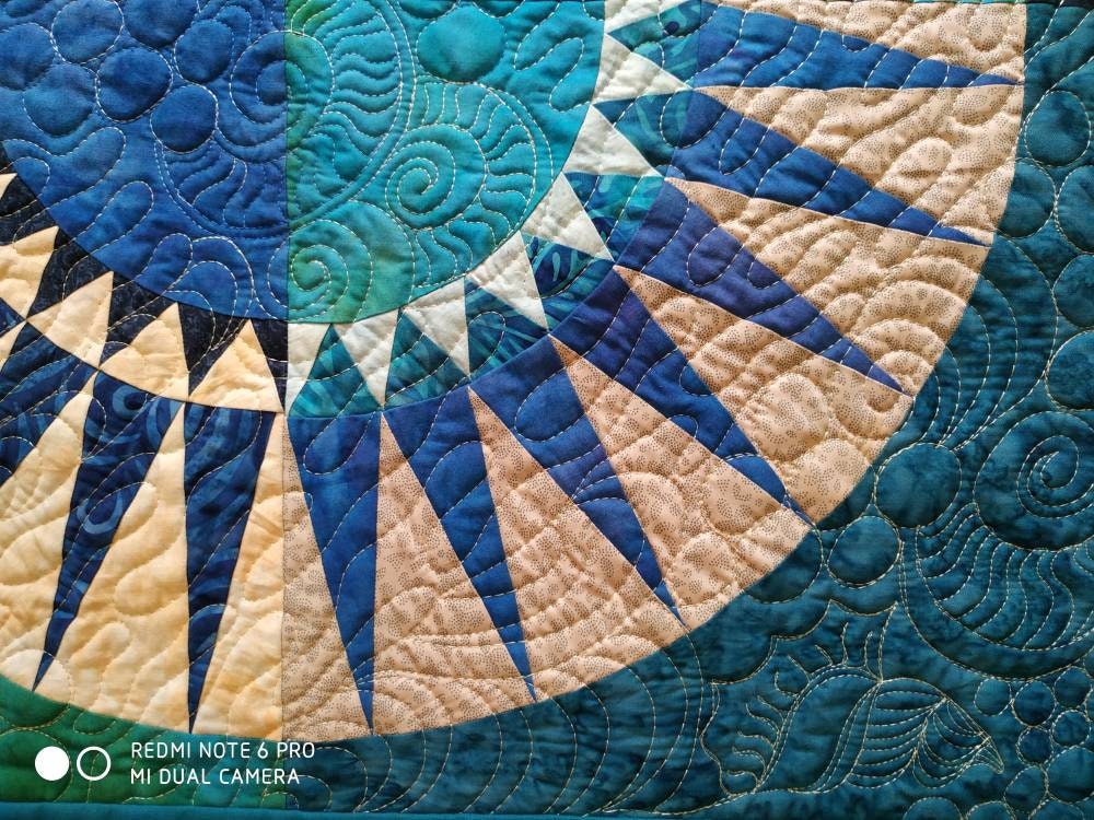 Close-up of intricate quilting depicting ocean waves and sea elements.