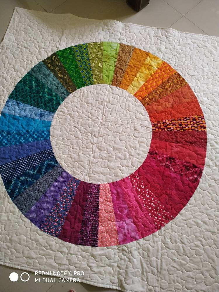 Modern  throw quilt with rainbow color theme on floor