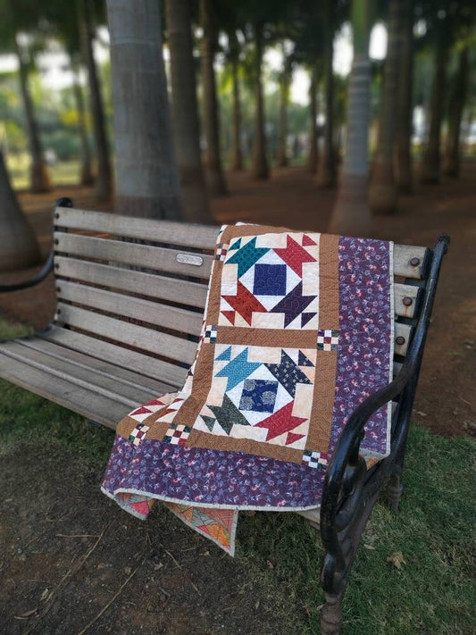 Country-style lap quilt draped on wooden bench