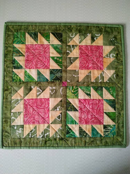 Rose-themed handmade doll quilt styled on table