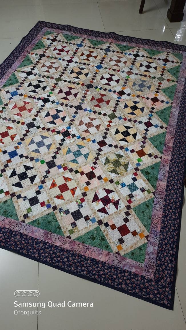 Full view of handmade patchwork quilt with traditional blocks and floral borders.