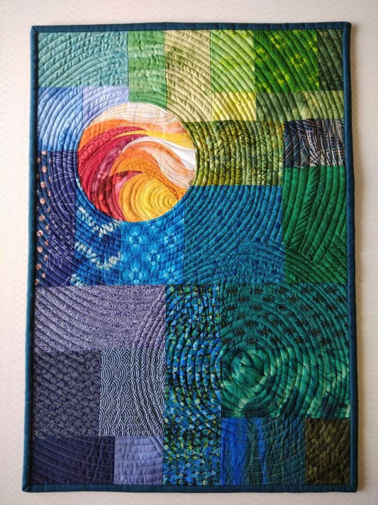 Abstract quilted wall hanging in blue and green with sun-like accents.