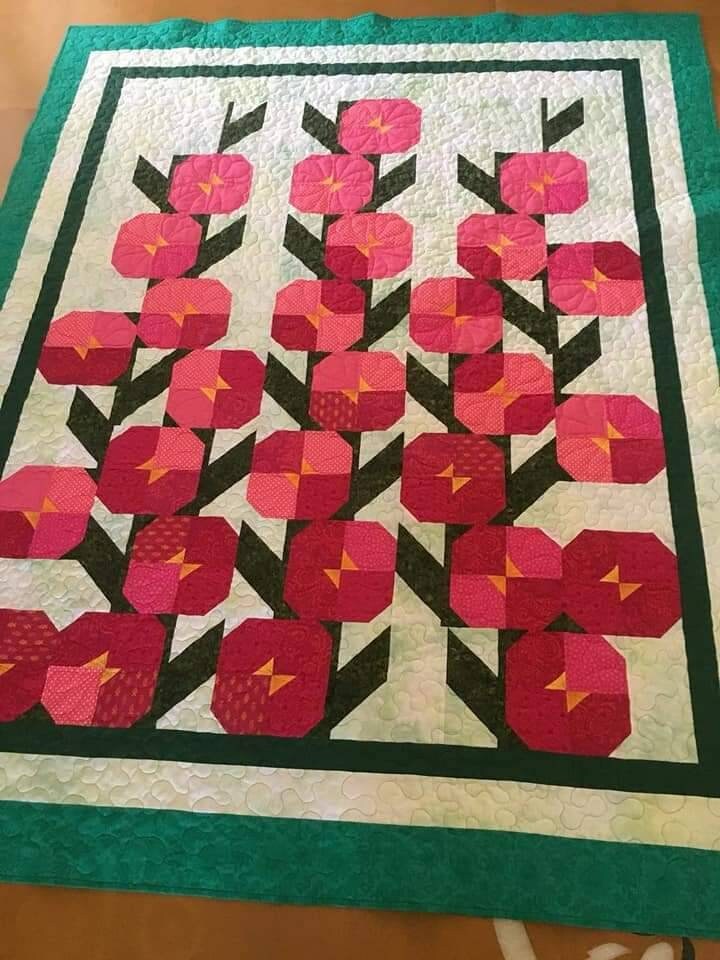Full poppies quilt displayed On floor