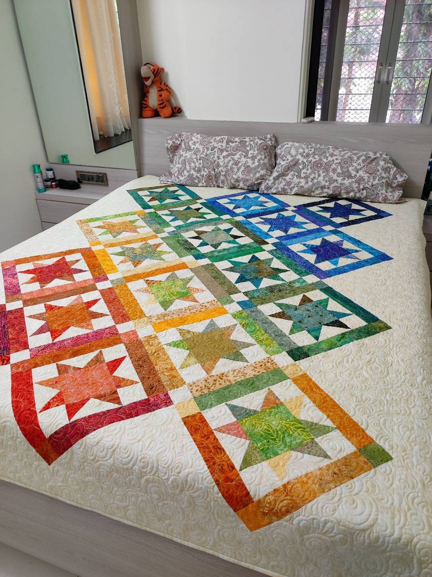 Twin size rainbow quilt styled on bed