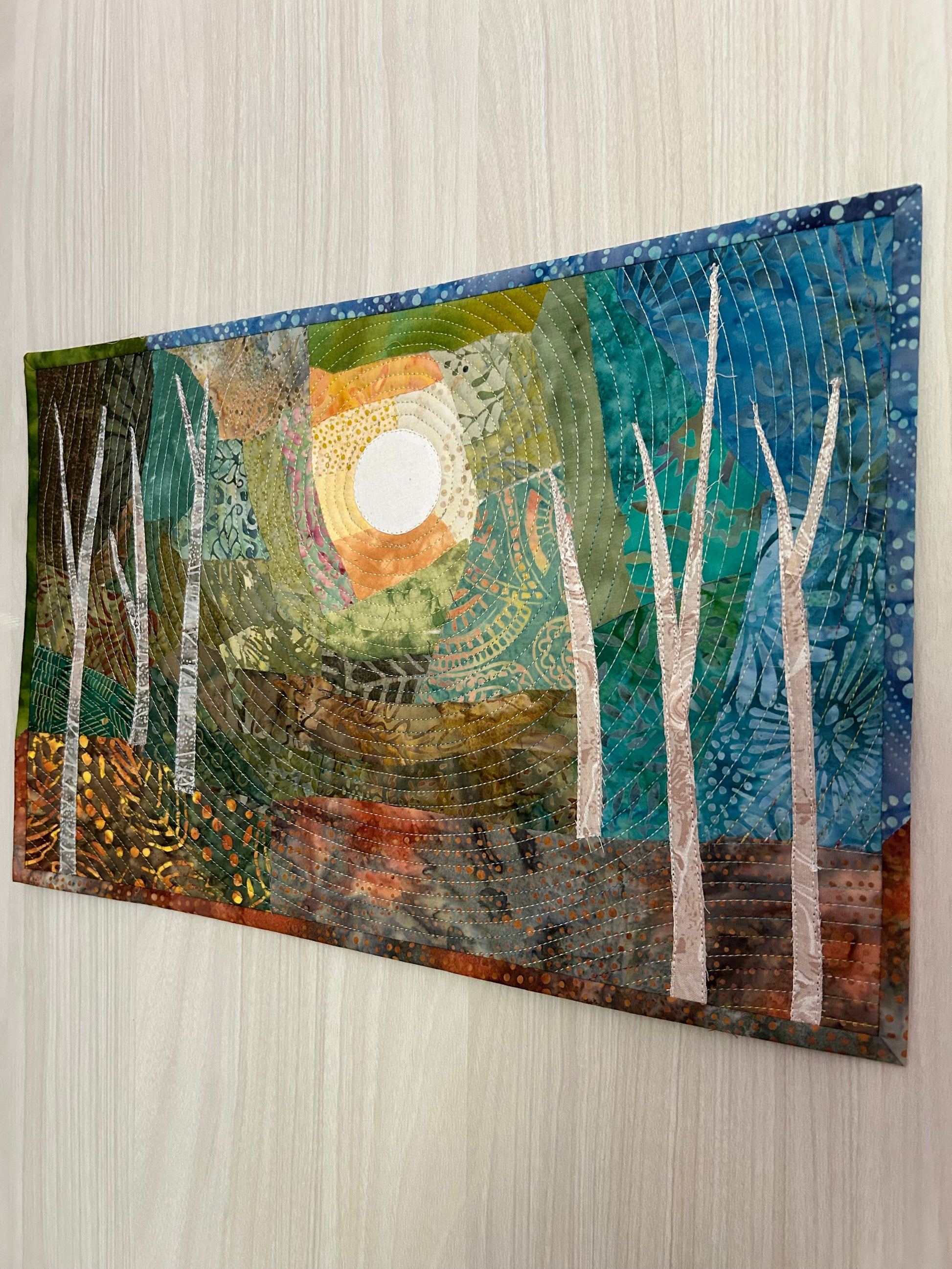 Side angle showing dimension and color gradient of jungle landscape quilt.