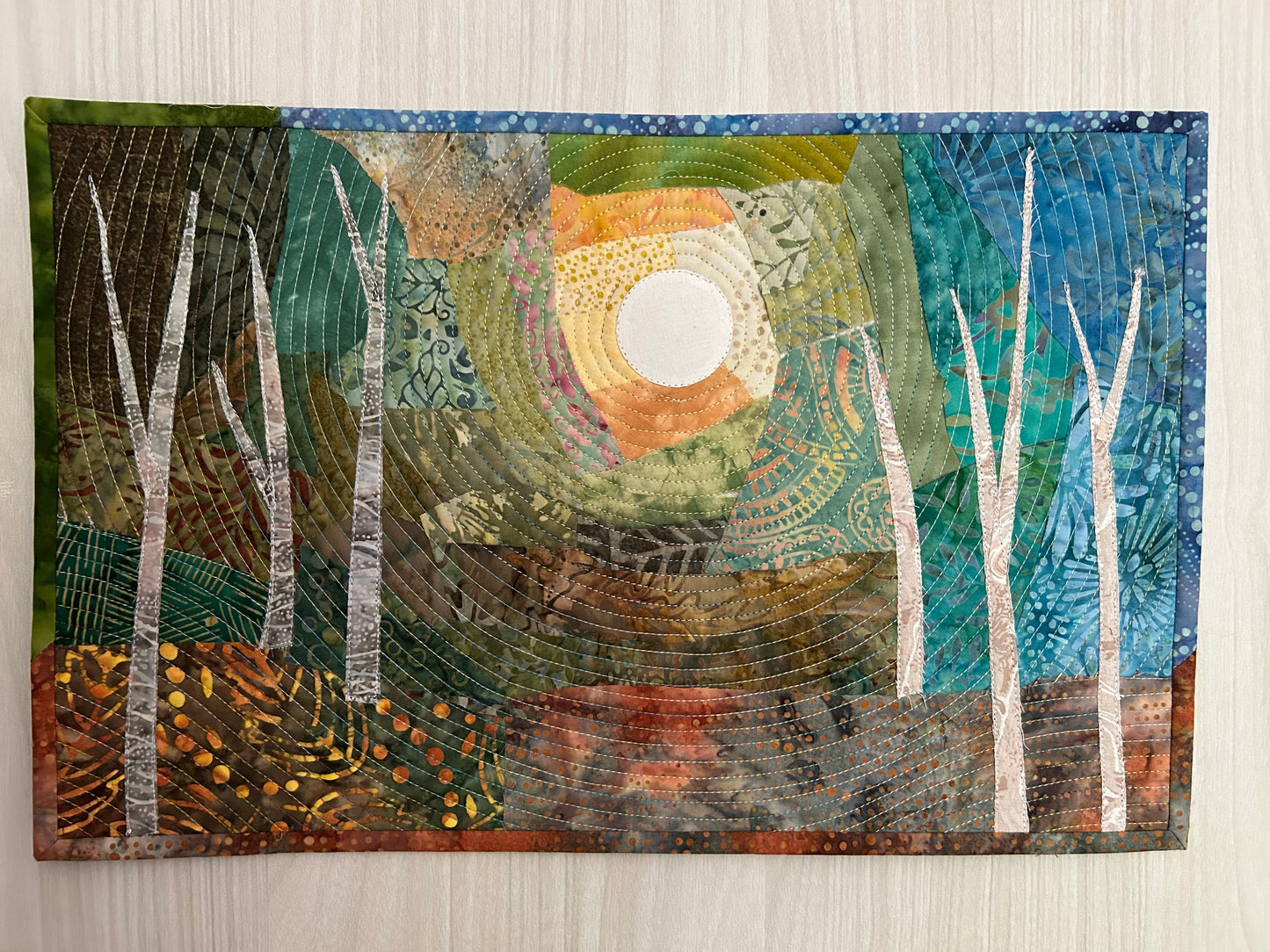 Full view of quilt hanging on white wall – contemporary textile wall art.