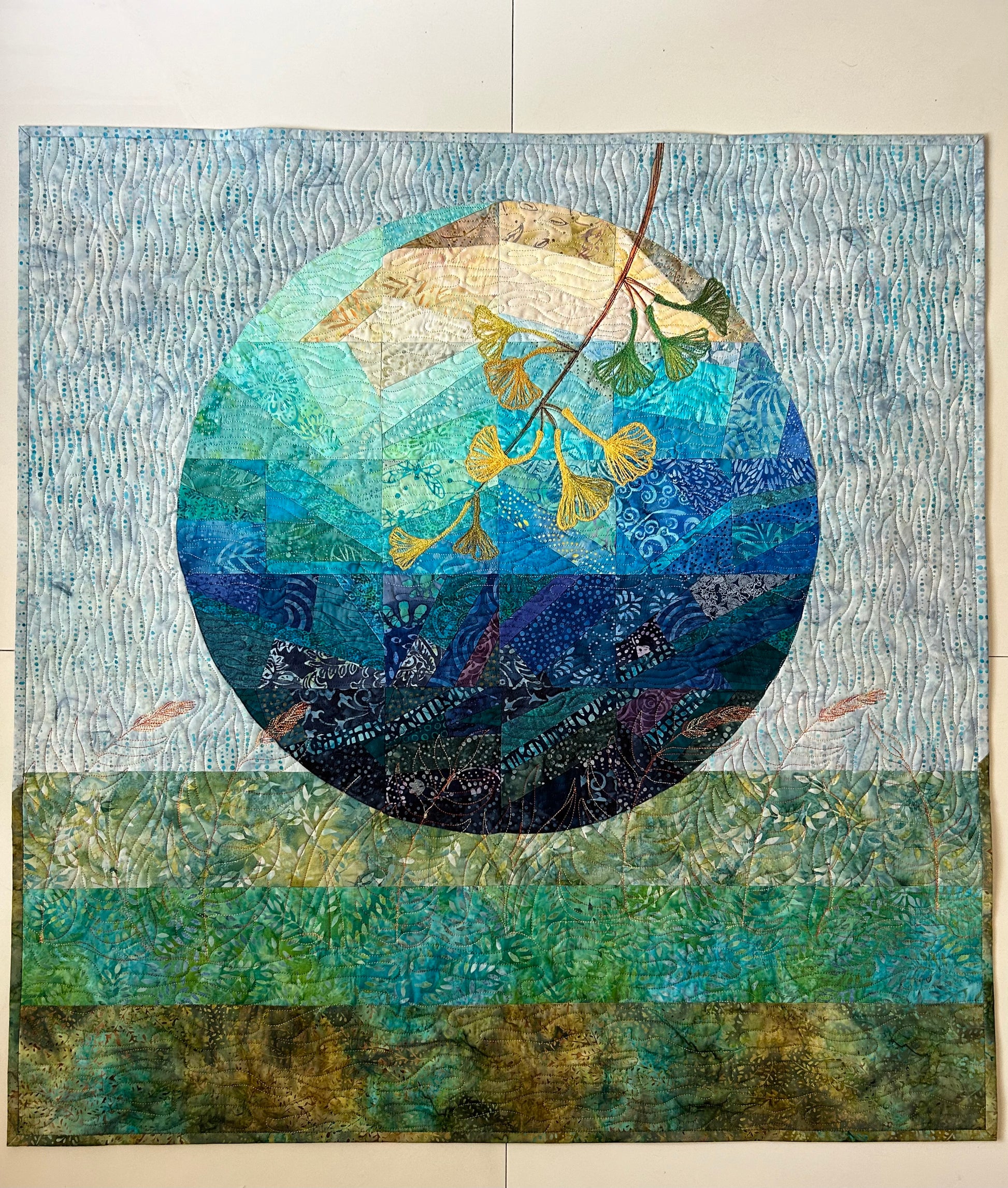 Abstract lunar art quilt – front view of moon-inspired blue and green fiber art.