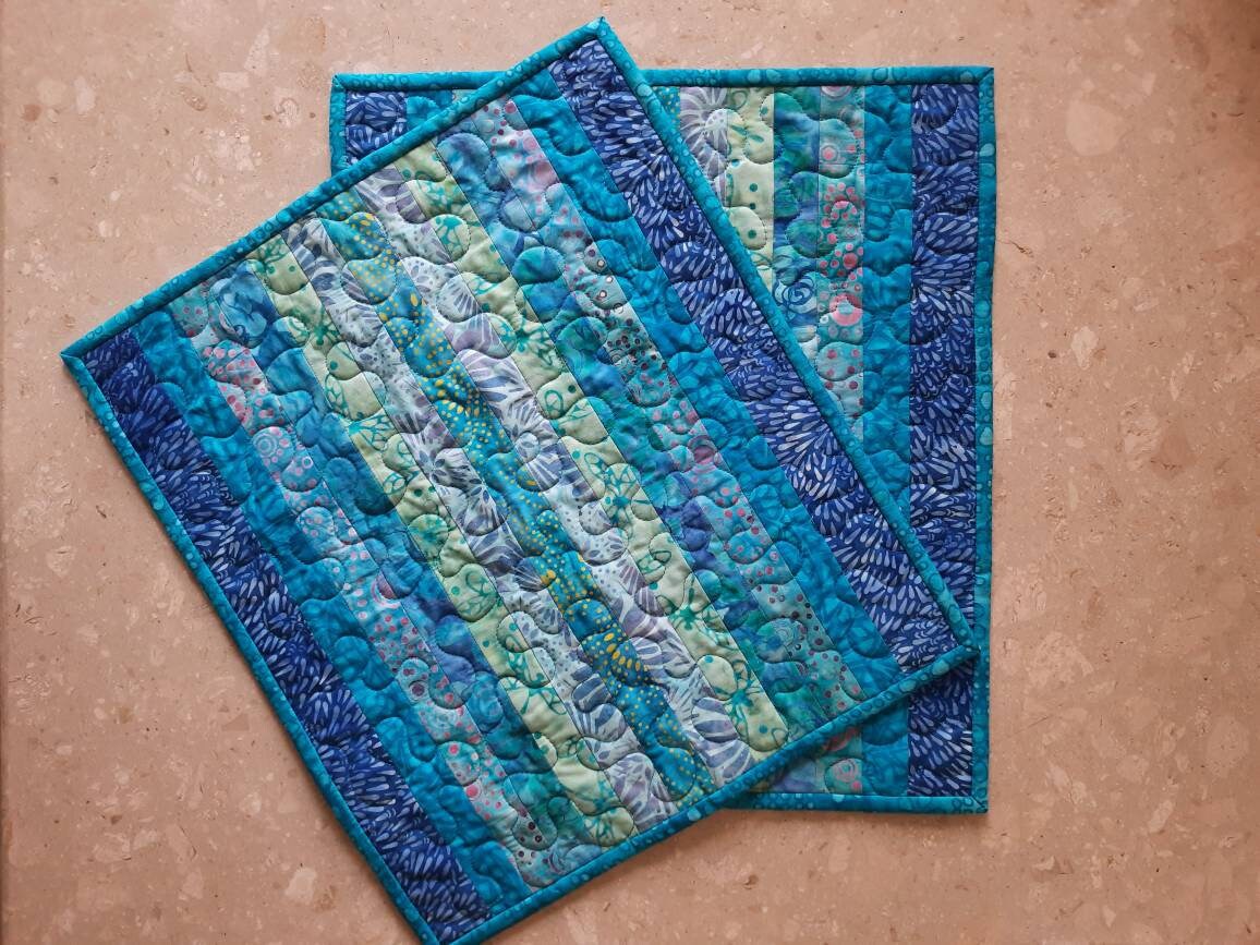 Set of two blue quilted placemats on wooden table
